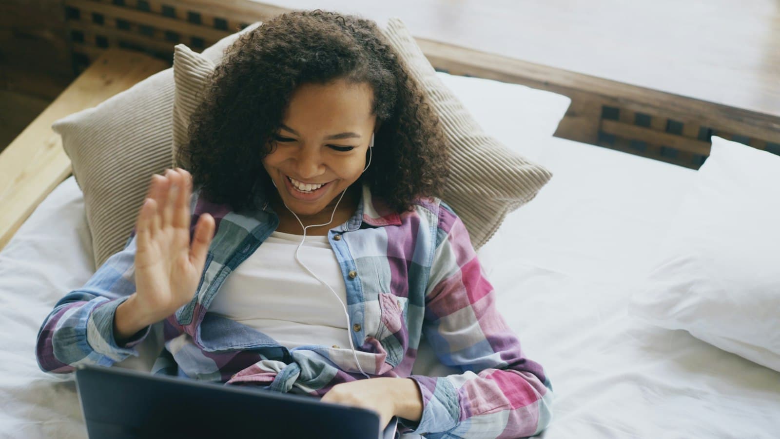 A young woman waving hello on a video call