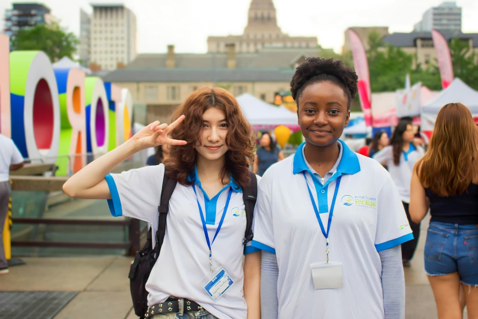 Two young women smiling at an outdoor community event