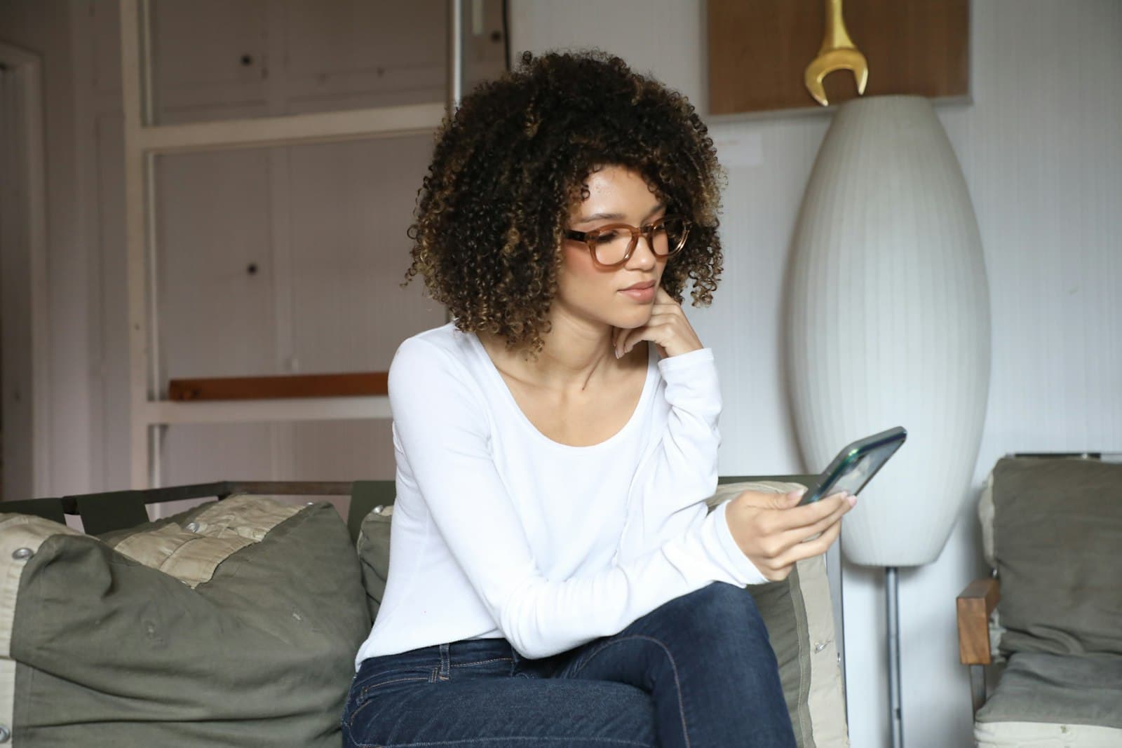 A woman sitting on her bed looking up a name on her phone